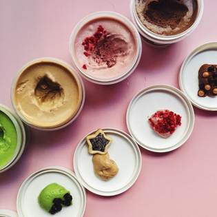 Various tiny bowls of spreads and desserts lined up against a pink table.